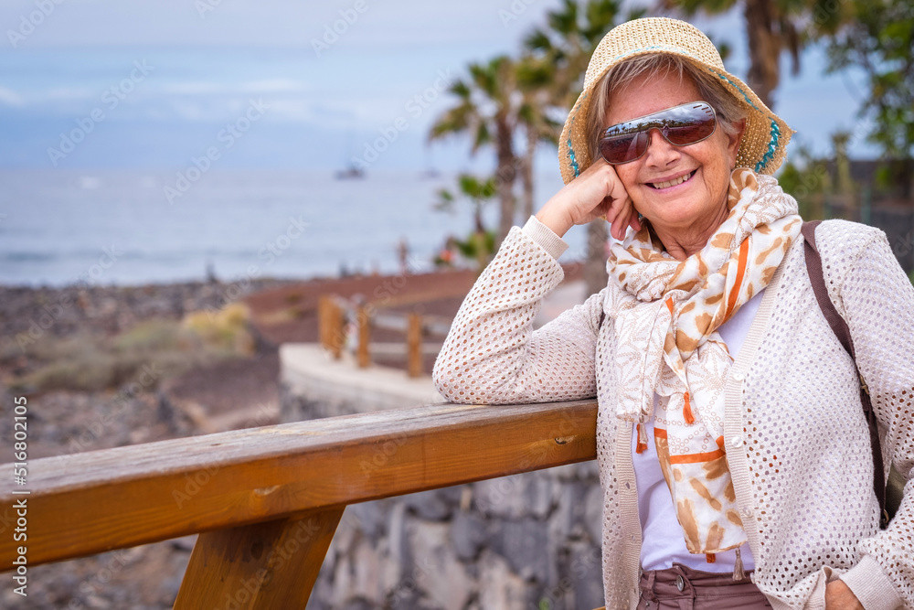 Portrait of happy traveler woman with hat and sunglasses enjoying relax in sea vacation looking at camera smiling.