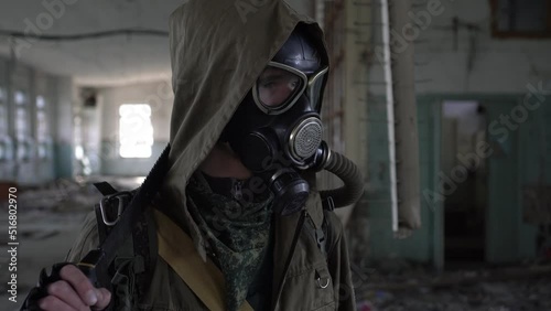 A man stalker in a gas mask stands in an abandoned building, close-up. The concept of post apocalypse and nuclear winter
