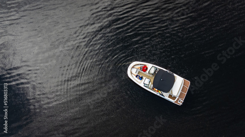 Aerial view of power boat anchored on dark waters of a lake.