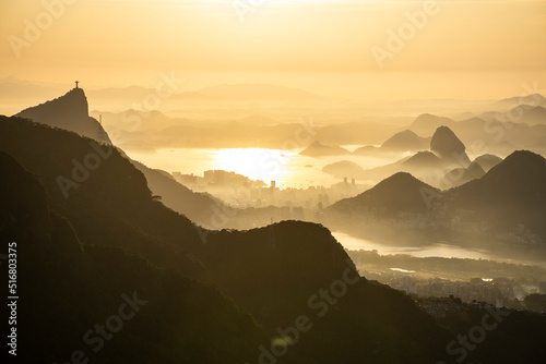 Beautiful view to layers of mountains and city during yellow sunrise photo