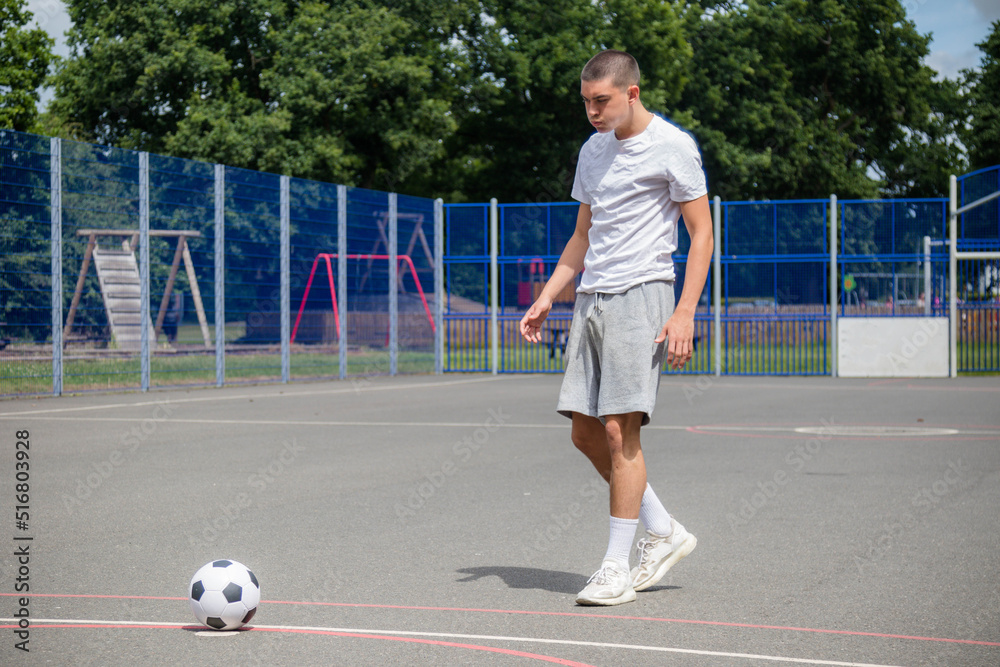 Obraz premium A Nineteen Year Old Teenage Boy Playing Football in A Public Park