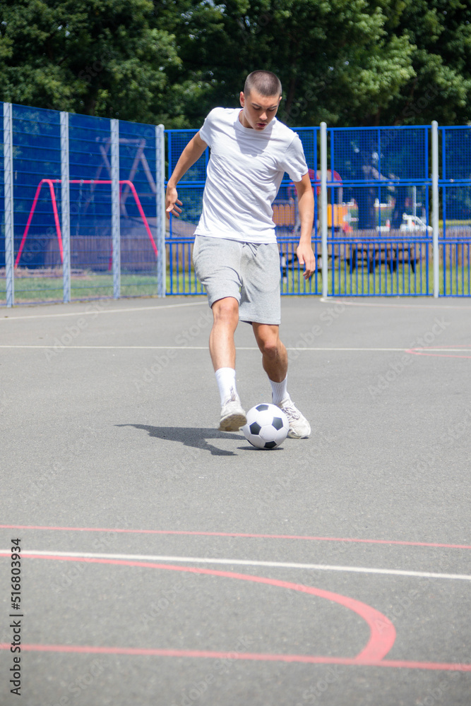 Obraz premium A Nineteen Year Old Teenage Boy Playing Football in A Public Park