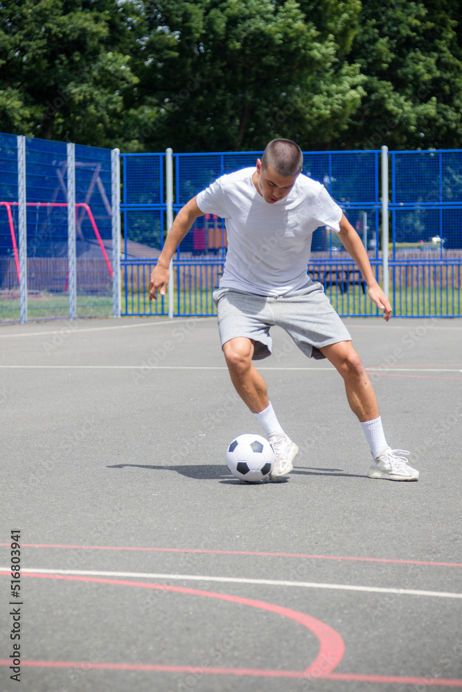 A Nineteen Year Old Teenage Boy Playing Football in A Public Park