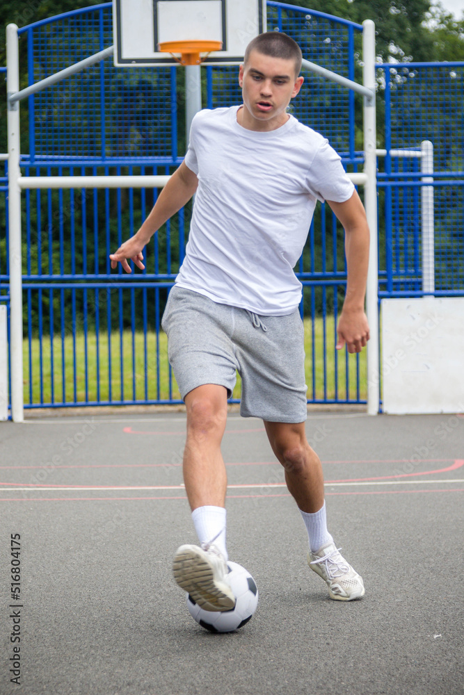 A Nineteen Year Old Teenage Boy Playing Football in A Public Park A Nineteen Year Old Teenage Boy Playing Football in A Public Park