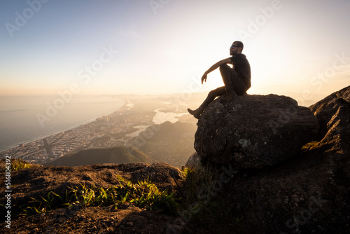 Man enjoying beautiful sunset view to city from rocky mountain top photo