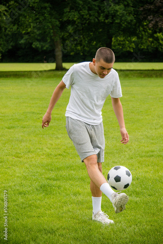 A Nineteen Year Old Teenage Boy Playing Football in A Public Park