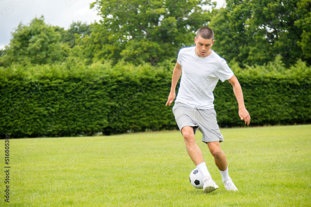 A Nineteen Year Old Teenage Boy Playing Football in A Public Park A Nineteen Year Old Teenage Boy Playing Football in A Public Park