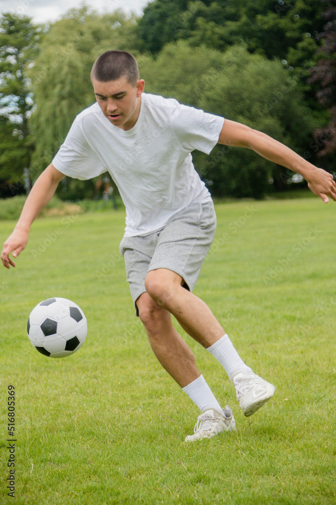 A Nineteen Year Old Teenage Boy Playing Football in A Public Park A Nineteen Year Old Teenage Boy Playing Football in A Public Park