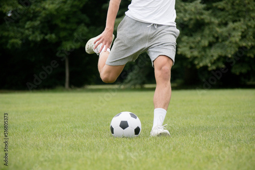 Fototapeta Naklejka Na Ścianę i Meble -  A Nineteen Year Old Teenage Boy Playing Football in A Public Park