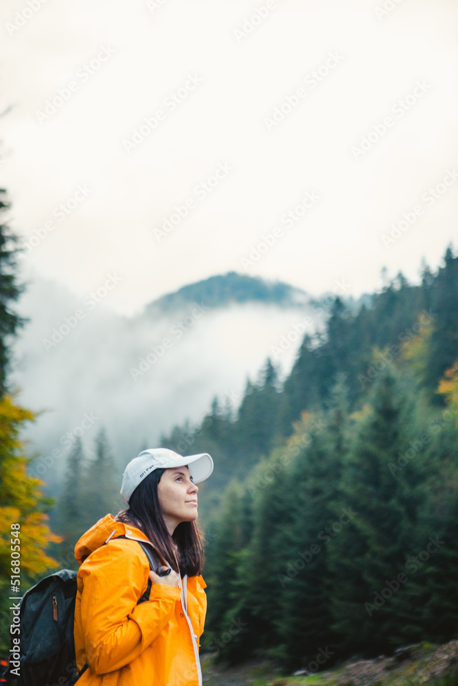 woman in yellow raincoat hiker in autumn mountains