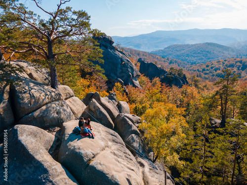 couple traveler sitting on the top of the rock with beautiful landscape of autumn forest