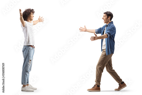 Full length profile shot of two male friends meeting each other with arms wide open