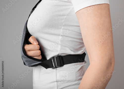 Woman wearing sling to support injured arm. Elbow, shoulder, forearm, wrist pain caused by trauma, injury, chronical disease. Healing process. High quality photo photo