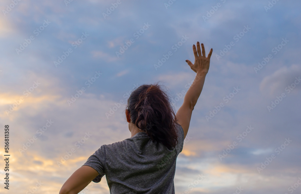 A single female figure with a gesture of congratulating success with a bright sky in the background A single female figure with a gesture of congratulating success with a bright sky in the background