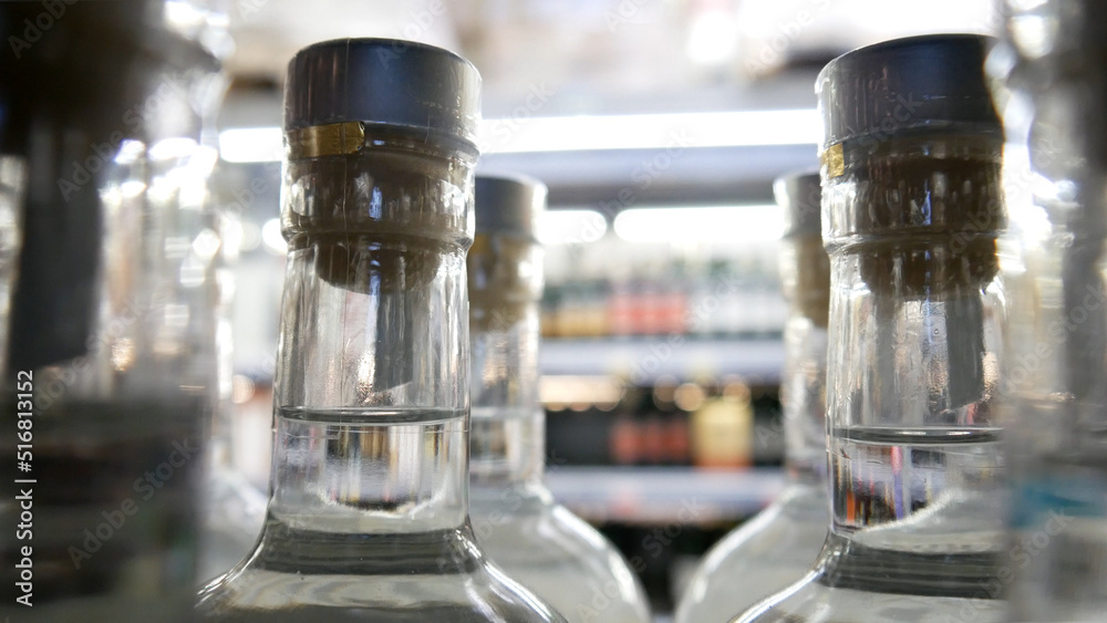 Close-up of glass bottles with gin or vodka on the shelf of an alcohol store Close-up of glass bottles with gin or vodka on the shelf of an alcohol store