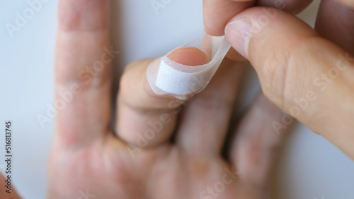 Photo Man putting medical adhesive tape waterproof sticking plaster on cuts wound on finger