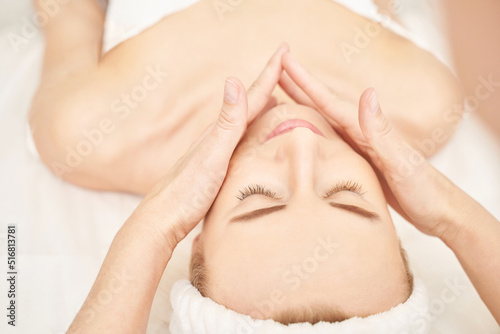 Face massage at luxury spa salon. Doctor hands. Pretty female patient. Beauty treatment. Healthy skin procedure. Young woman head. Light background. Facial rejuvenation dermatology mask. Detox therapy