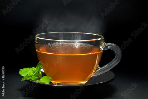 Cup with mint leaves on black background, closeup
