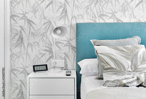 Cosy bedroom with grey pillows,  turquoise headboard and white bedside table