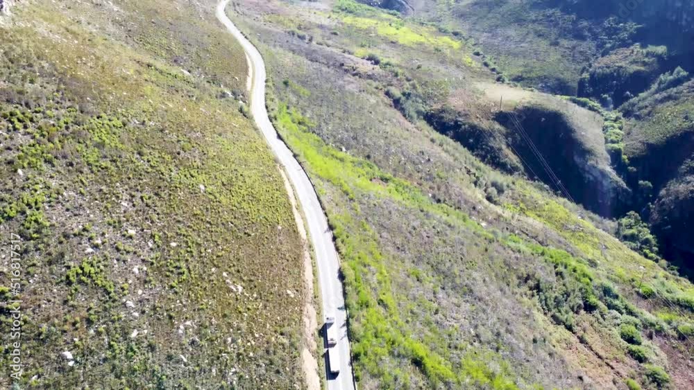 Aerial view looking down on thin tarmac road running up a mountain pass with one truck driving up the road Aerial view looking down on thin tarmac road running up a mountain pass with one truck driving up the road