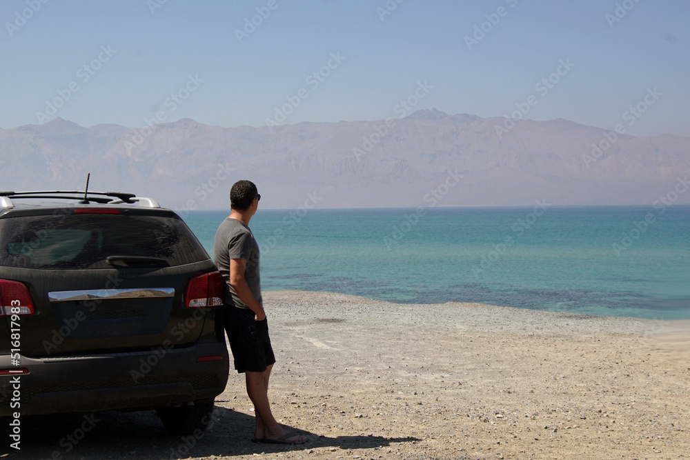 Lonely man stands near car parked at the blue sea. Lonely man stands near car parked at the blue sea.