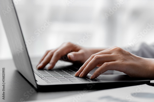 A woman typing on a laptop keyboard, she is filling out her credit card information to pay for an order on an Internet shopping site. Online shopping and credit card payment concept.