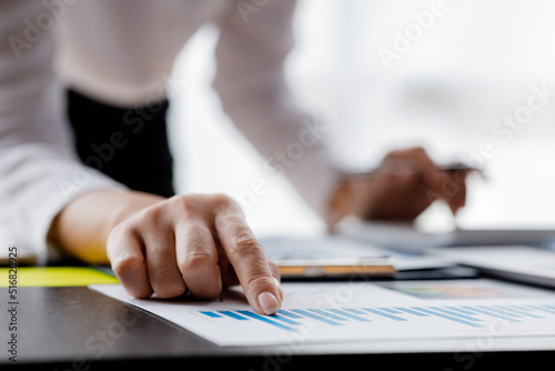 Close-up the businesswoman's hand pointing at a bar chart on a corporate financial information sheet, the businesswoman examines the financial information provided by the finance department.