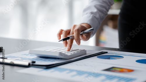 Businessman using a calculator to calculate numbers on a company's financial documents, he is analyzing historical financial data to plan how to grow the company. Financial concept.