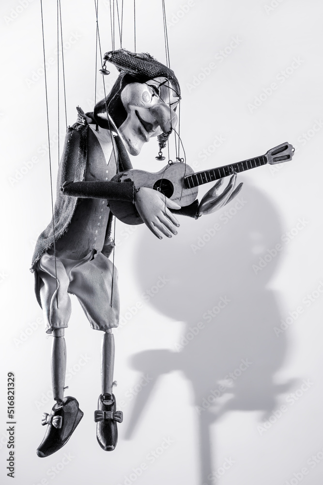 Harlequin puppet doll on strings on white with selective focus black and white