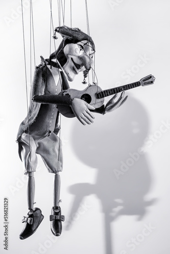 Harlequin puppet doll on strings on white with selective focus black and white photo