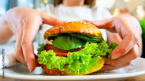 Vegan sandwich healthy vegetarian burger. Cute cheerful girl eating veggie hamburger with salad, avocado, vegetable. Vegetarian diet food concept.