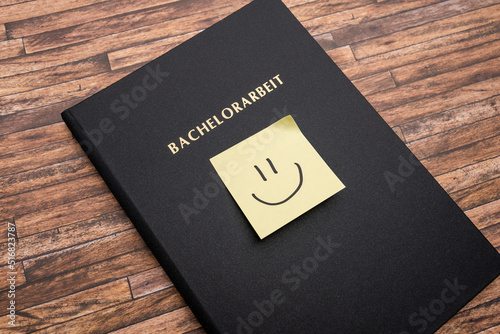 Adhesive note with a smiley on a Bachelorarbeit (bachelor thesis). Printed and bound thesis with a black cover. Finishing studies in Germany and becoming a graduate student.