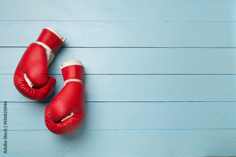 Red boxing gloves on wooden background, top view