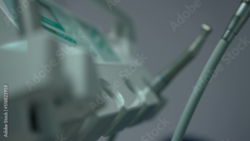 Close-up dentist hand taking handpiece in slow motion leaving. Unrecognizable expert professional working in dental clinic indoors. Orthodontics and stomatology concept photo