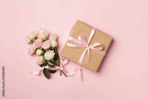 Gift box and rose flowers on color background, top view © Liami