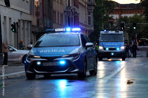 Incydent policji wieczorem w mieście. - Sygnalizator błyskowy niebieski na dachu radiowozu policji polskiej w nocy.