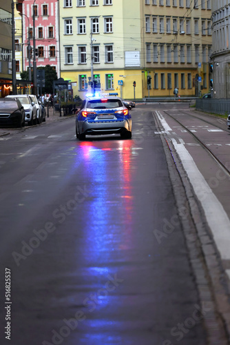 Incydent policji wieczorem w mieście. - Sygnalizator błyskowy niebieski na dachu radiowozu policji polskiej w nocy.