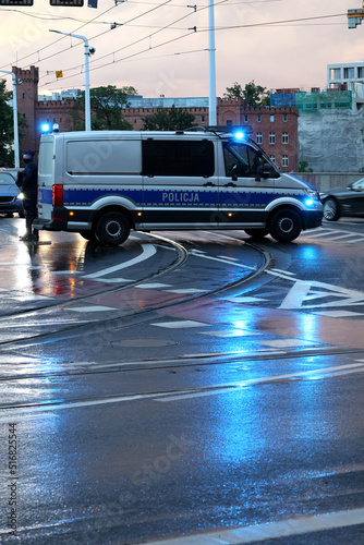 Incydent policji wieczorem w mieście. - Sygnalizator błyskowy niebieski na dachu radiowozu policji polskiej w nocy.