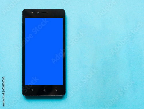 A black smartphone with a blue screen on a blue background. Copy space.