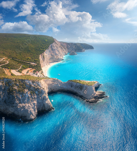 Aerial view of blue sea, mountain cape, sandy beach, sky with clouds at sunrset in summer. Porto Katsiki, Lefkada island, Greece. Beautiful top view of sea coast, rocks, azure water, green forest