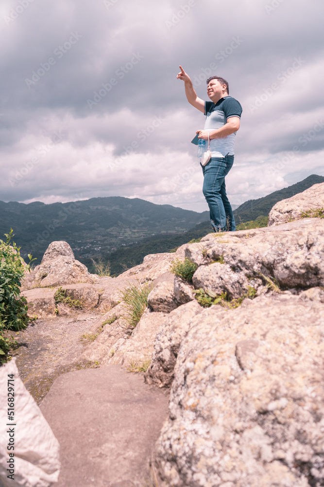 Medium build middle aged adult pointing to the sky on top of a boulder Medium build middle aged adult pointing to the sky on top of a boulder