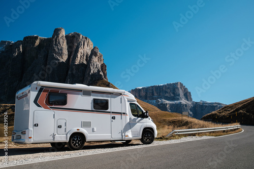 RV Caravan family car on vocation in Dolomites Alps with rocky mountains on a background . Beautiful nature in early autumn season.