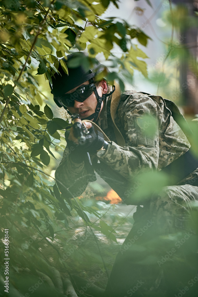 Ukrainian soldier sniper in the forest with machine gun