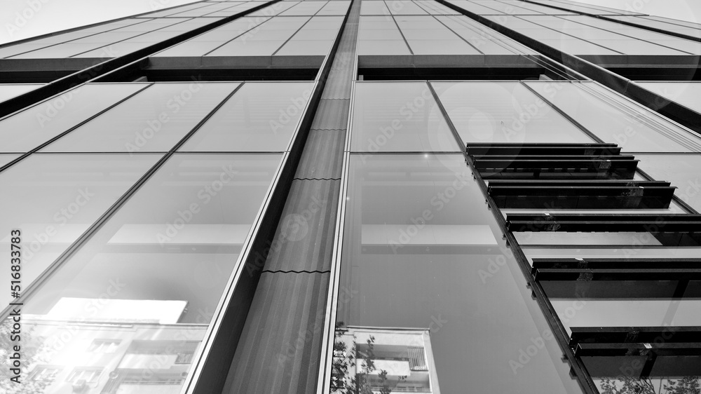 Bottom view of modern skyscraper in business district against blue sky. Looking up at business buildings in downtown. Rising sun on the horizon. Black and white. Bottom view of modern skyscraper in business district against blue sky. Looking up at business buildings in downtown. Rising sun on the horizon. Black and white.