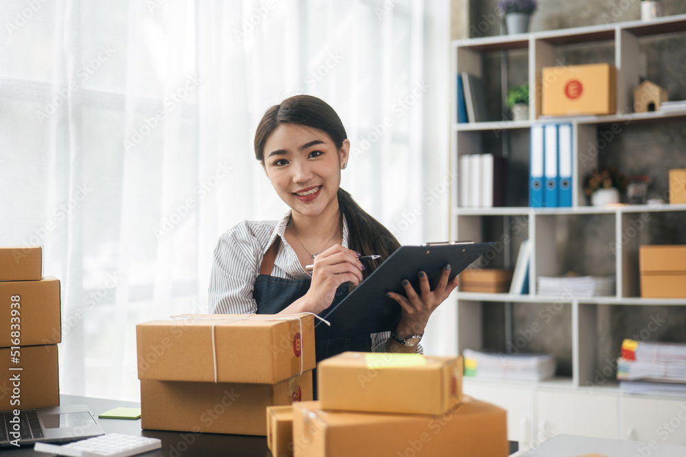 Business woman happy and cheerful for successful for receiving orders from customer via laptop with a lot of parcel boxes for shipping.