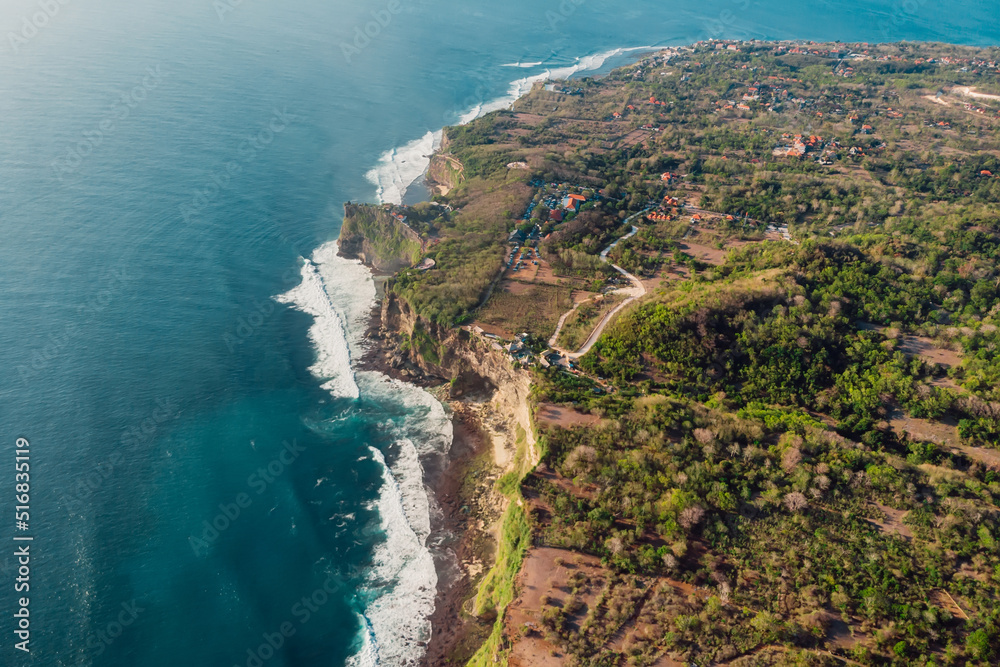 Aerial view of scenic coastline with cliffs and ocean with waves in Uluwatu, Bali