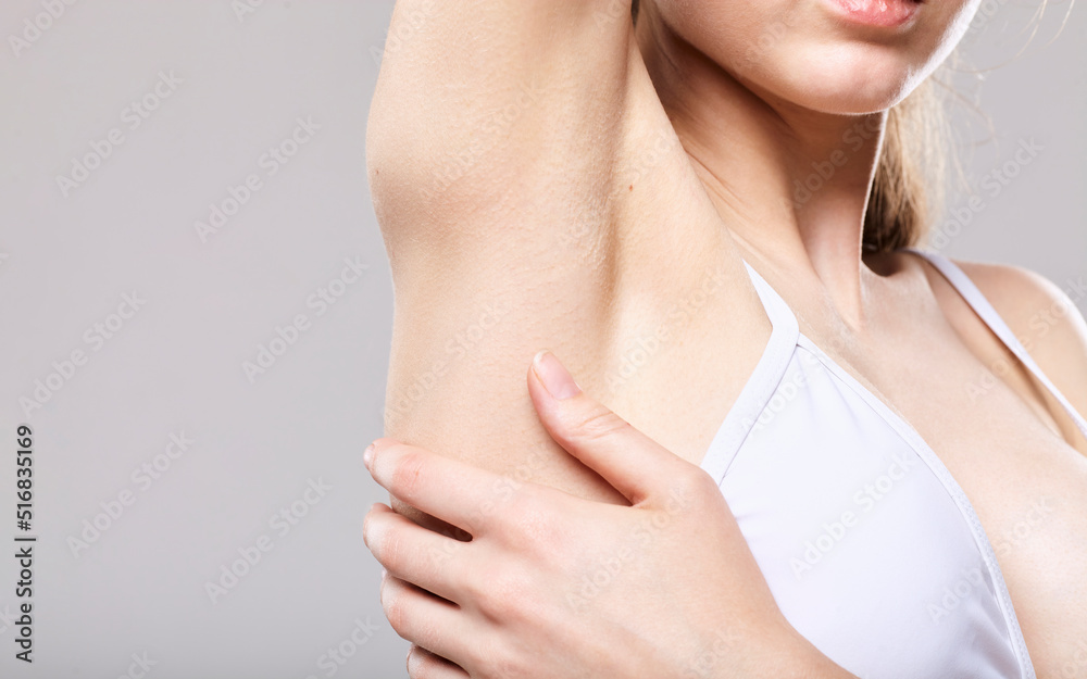 a woman on a gray background shows off her shaved armpit a woman on a gray background shows off her shaved armpit