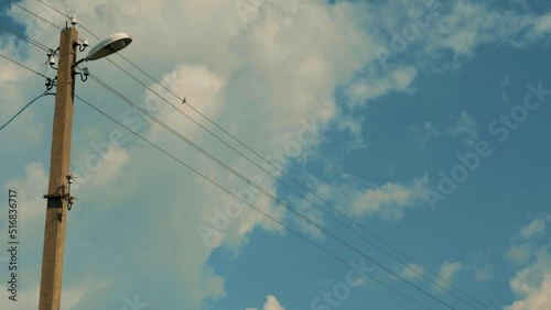 a small bird is sitting on an electric wire near a lamppost