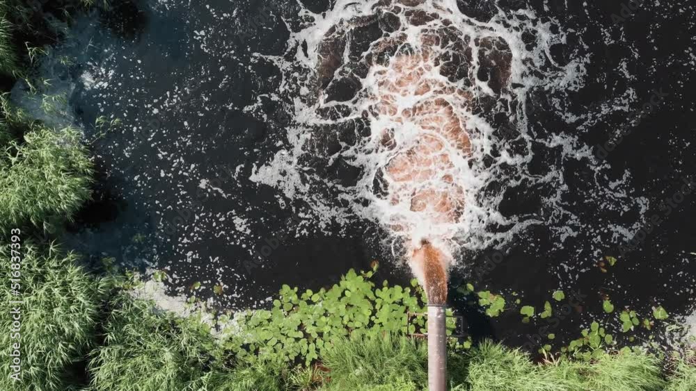 The industrial wastewater is discharged from the pipe into the river.