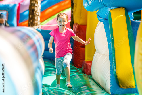 Foto Happy little girl having lots of fun on a jumping castle during sliding